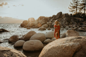Elopement Photographer, a couple embraces on large boulders near a lake at golden hour